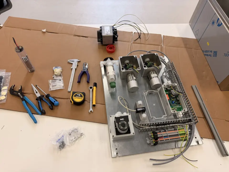 Industri&euml;le componenten voor een elektrische schakelkast, aansluitklemmen, sensoren en montagegereedschap op een werkbank in de werkplaats van Neohance.
